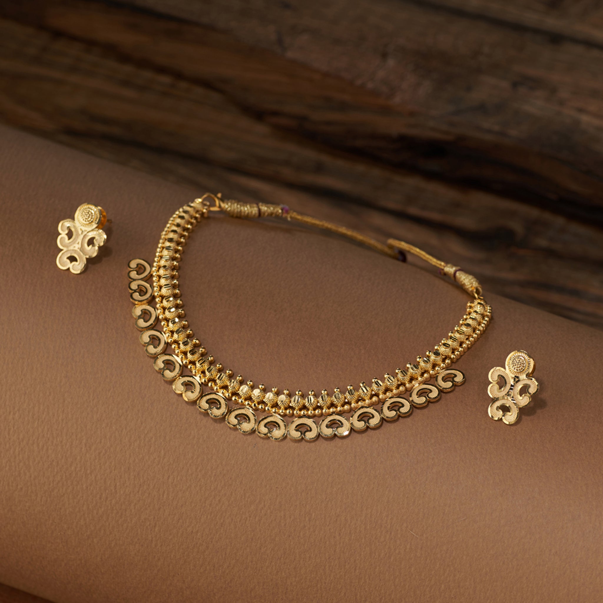 High gold-forming necklace set with intricate carved motifs, paired with matching designer earrings.