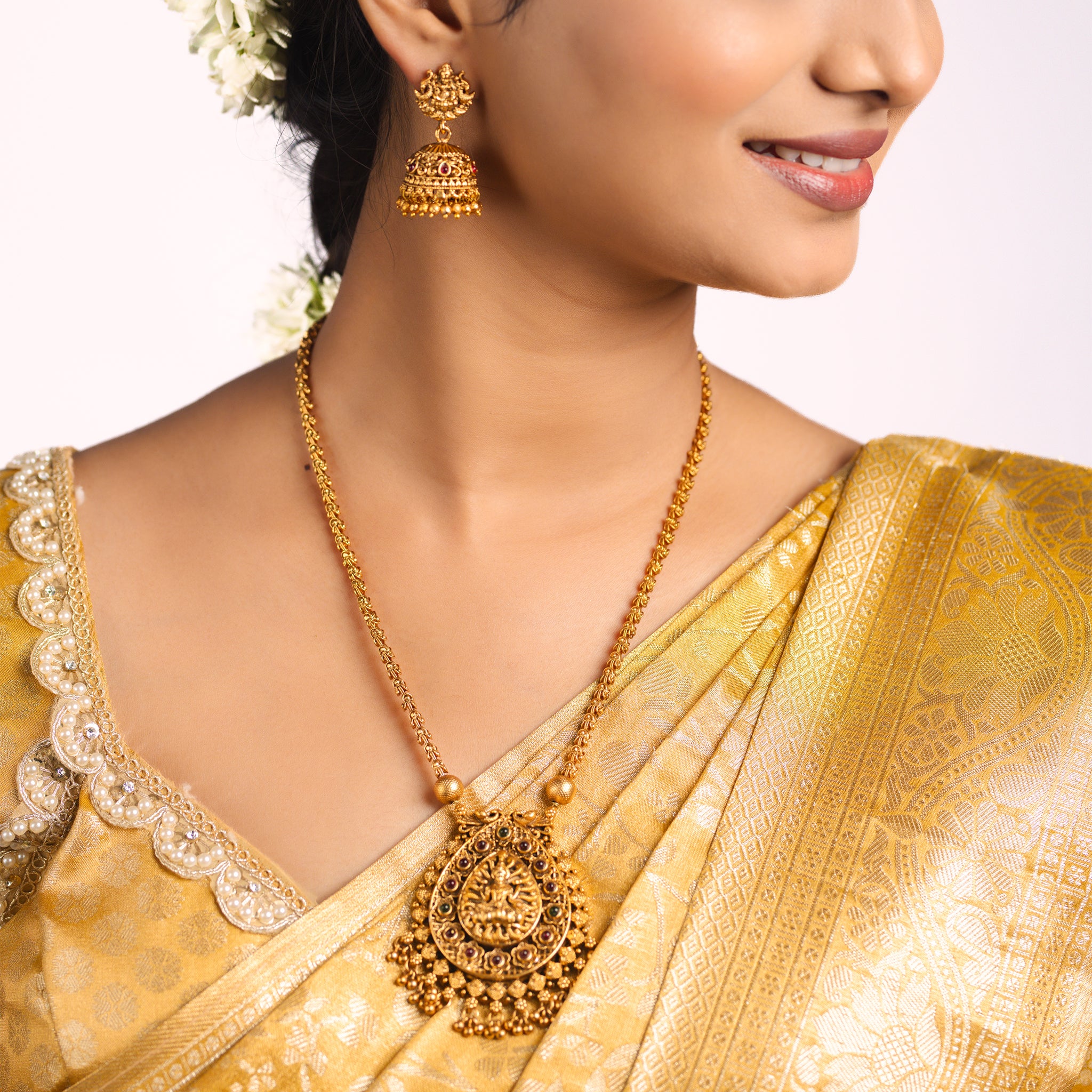 Woman wearing a gold saree with matching south Indian Temple jewelry with Lakshmi Motif. Temple Jewellery Lakshmi | Tilloma