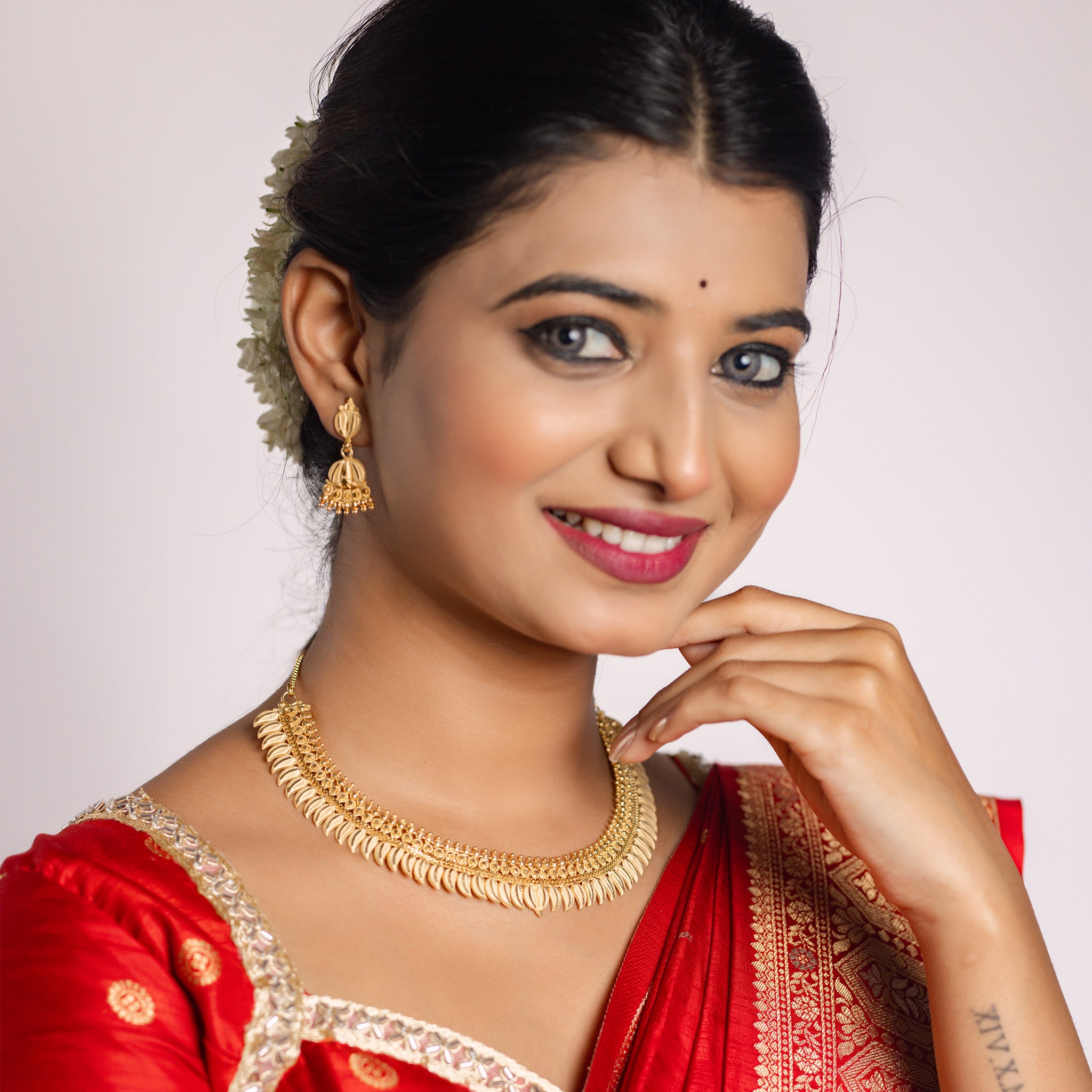 Woman in a red saree with gold imitation jewelry. Gold Forming Necklace Set | Kumarika by Tilloma