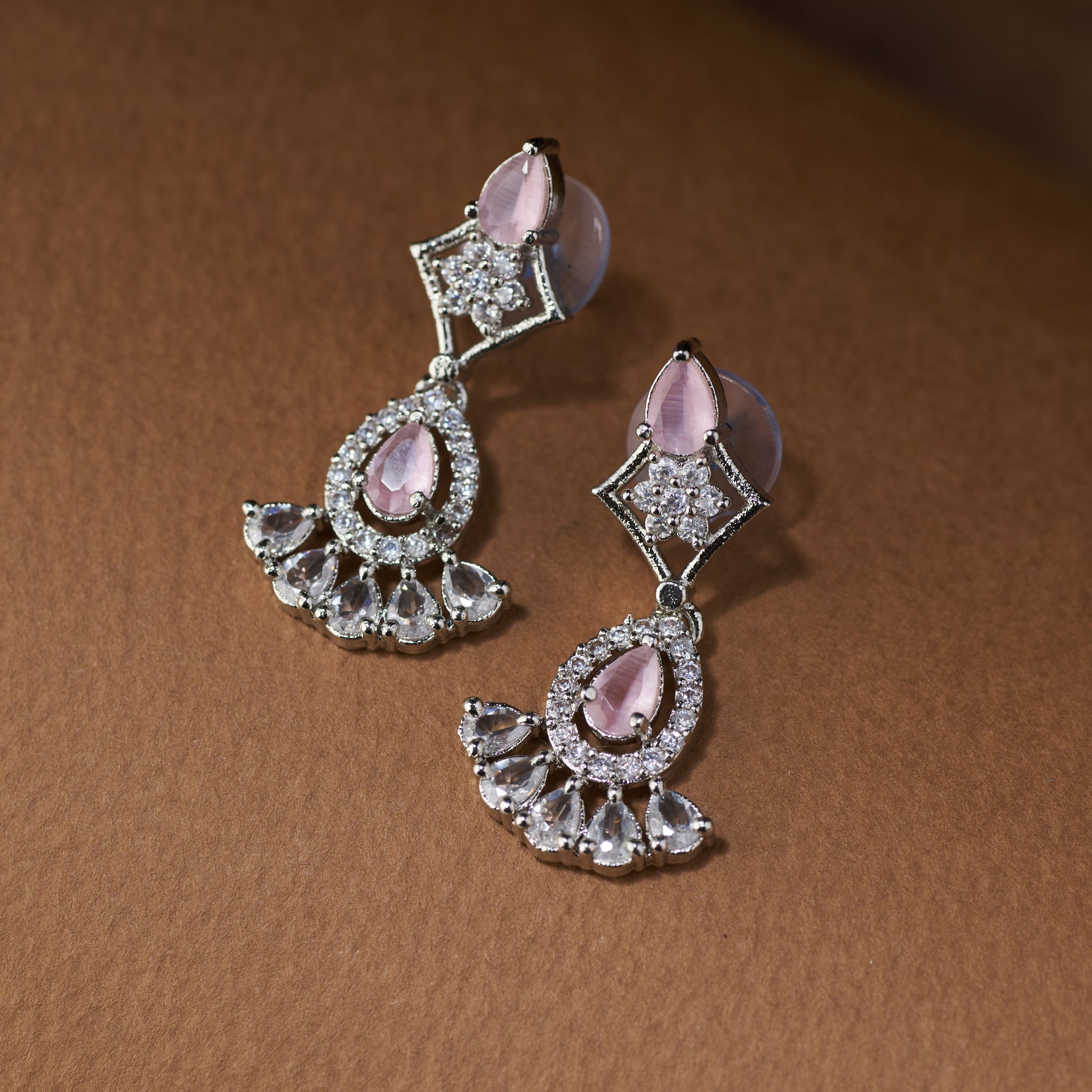 Teardrop Necklace and earrings with pink cubic zircon stones on a brown surface