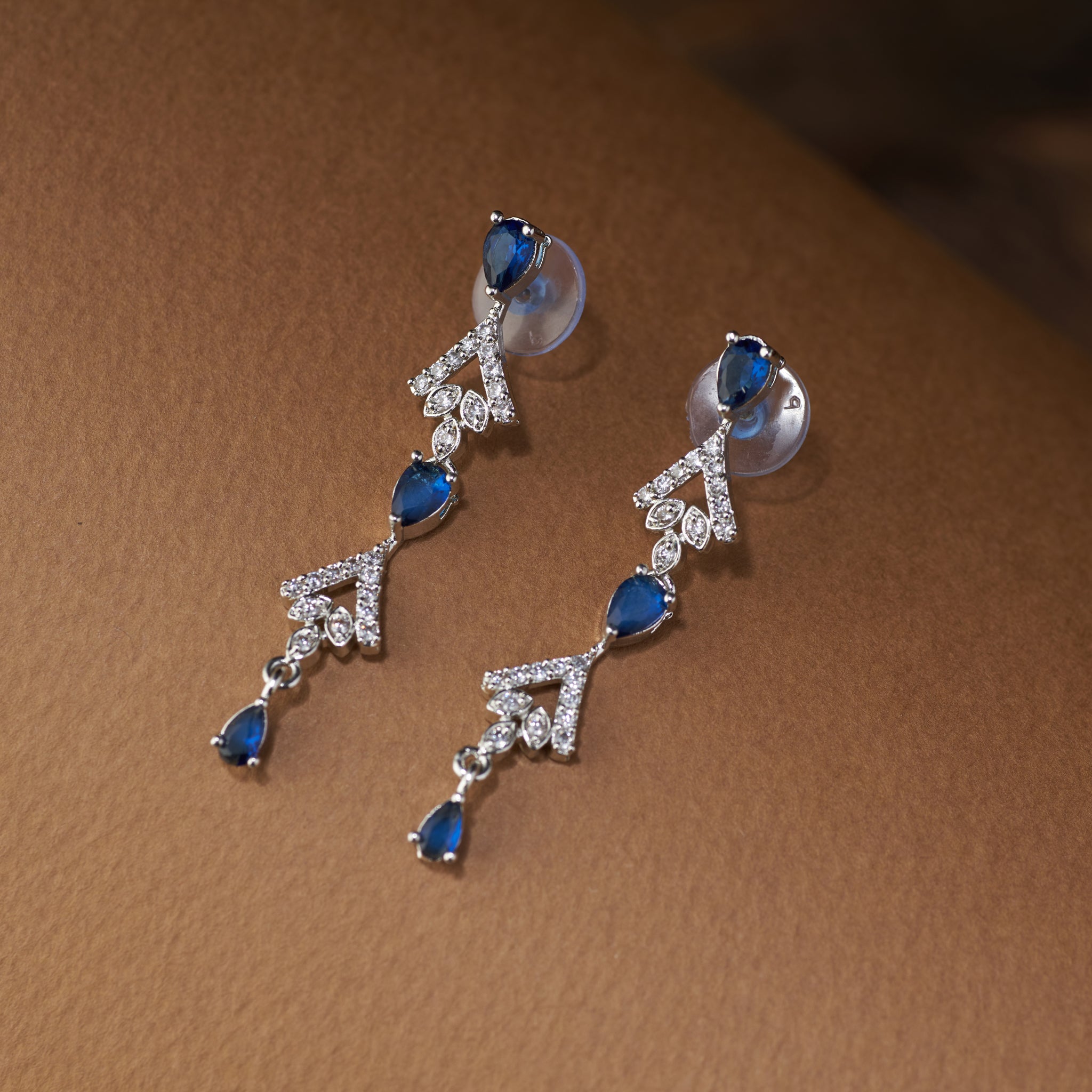 Teardrop Necklace and earrings with blue cubic zircon stones and silver accents on a brown background