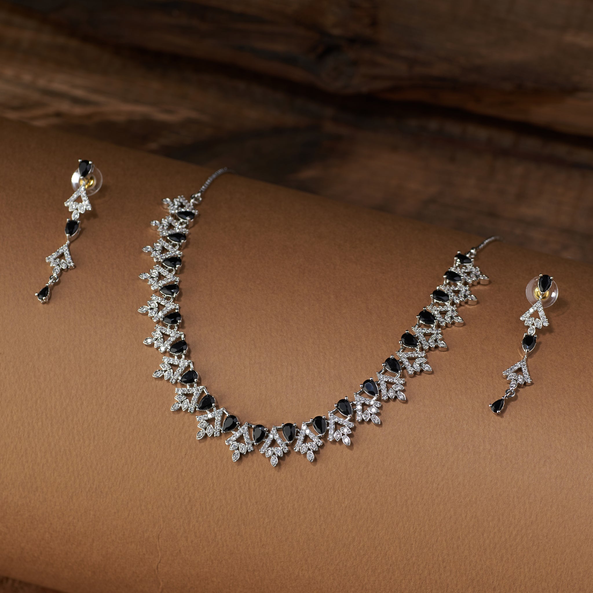 Teardrop Necklace and earrings with black cubic zircon stones and silver accents on a brown background