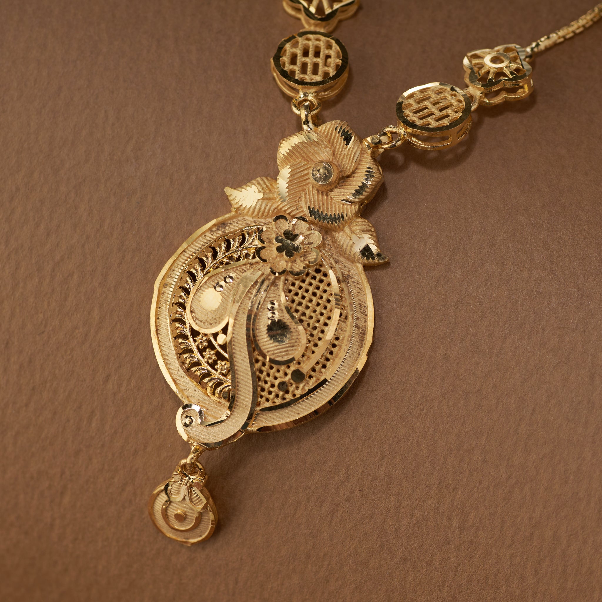 High gold long necklace set with intricate filigree pendant and matching drop earrings close up