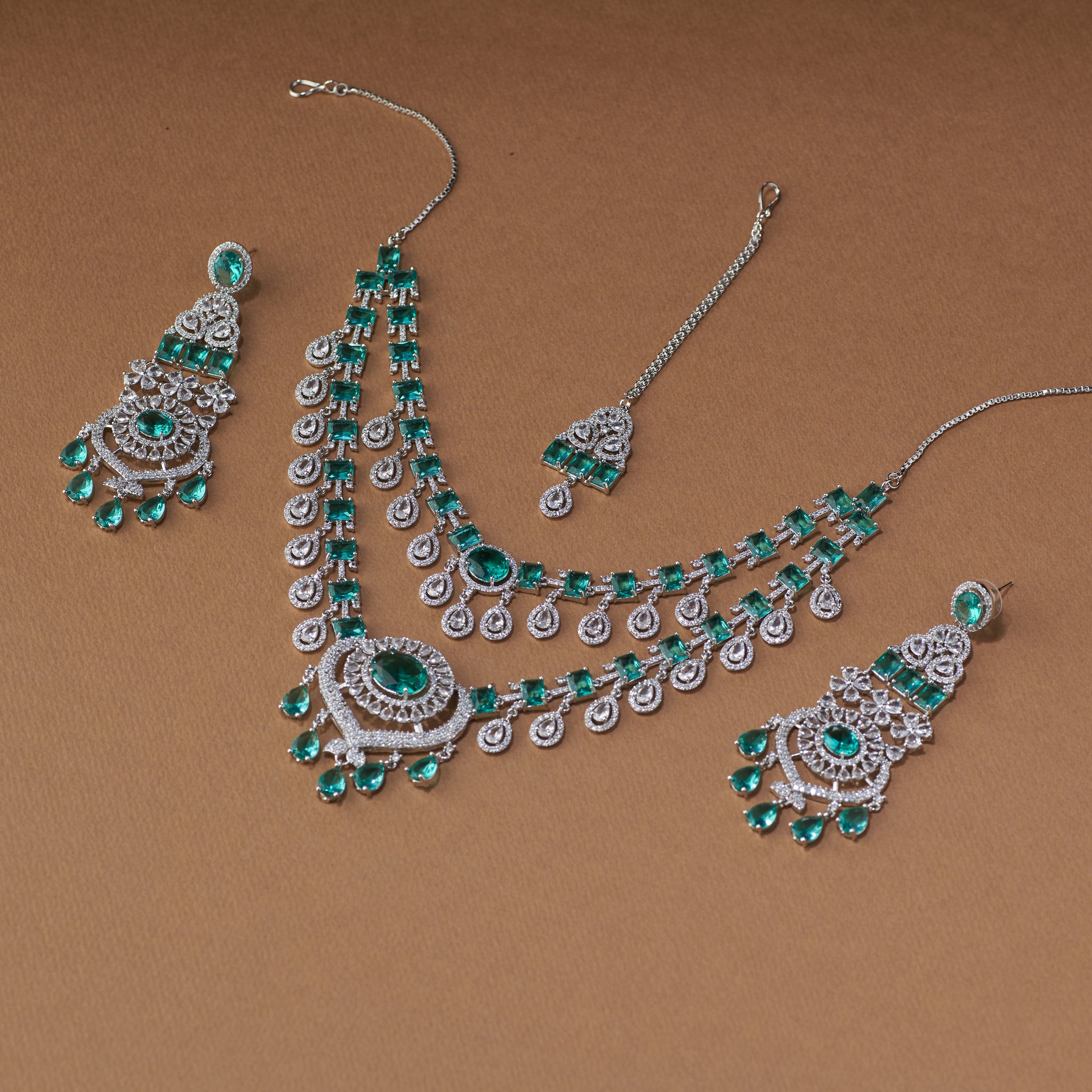 Elegant emerald and diamond bridal jewellery set with necklace, earrings, and maang tikka for weddings and special occasions.