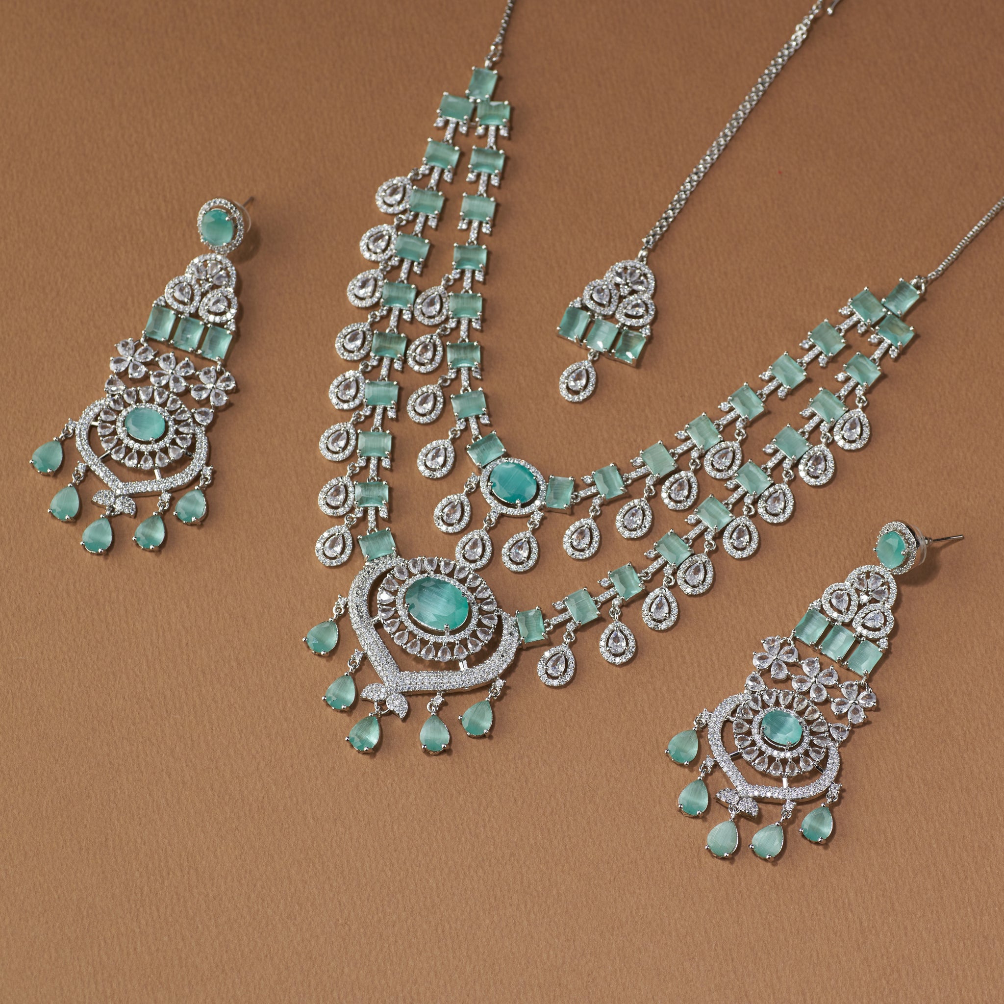 Elegant emerald and diamond bridal jewellery set with necklace, earrings, and maang tikka for weddings and special occasions.
