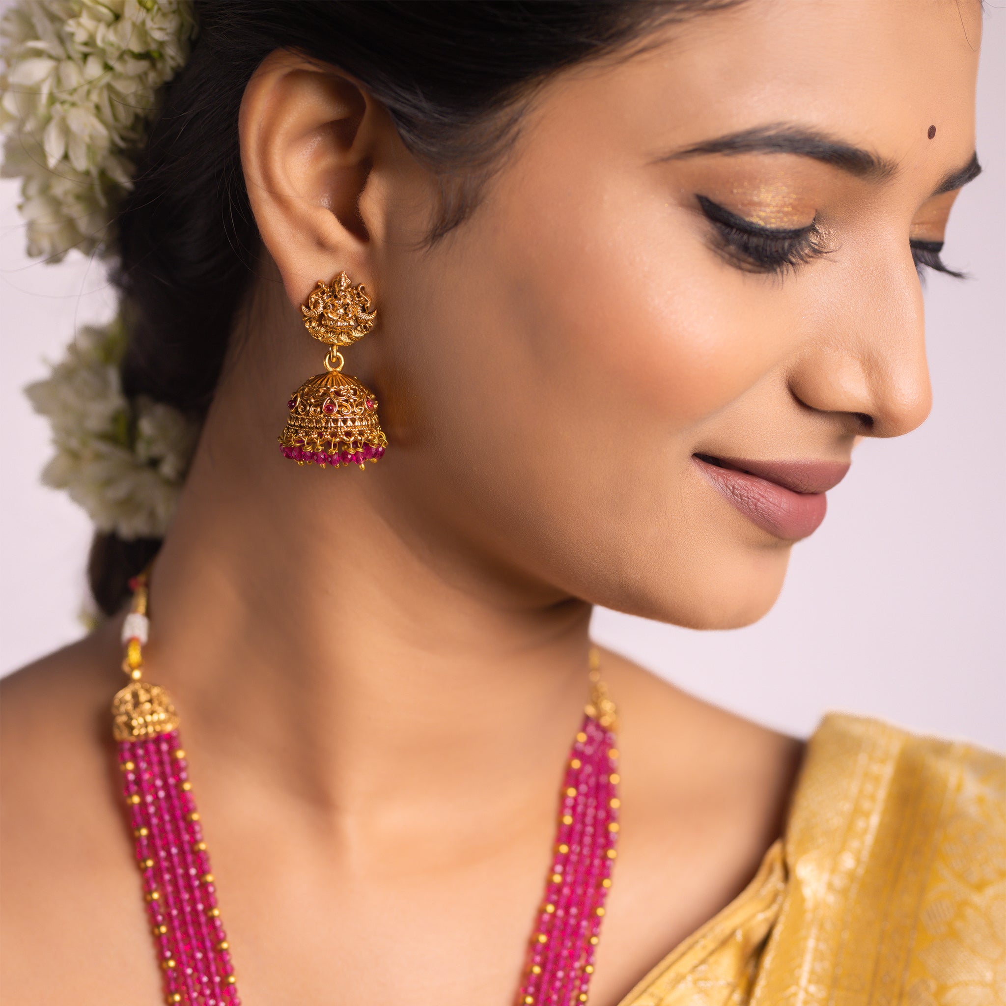 Woman wearing gold and pink traditional jewelry with a blurred background