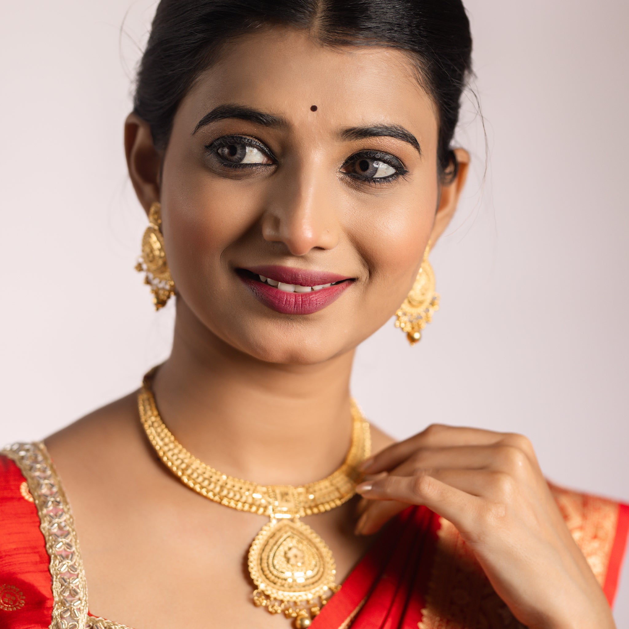 Woman wearing gold jewelry and a red outfit. Gold Forming jewellery, short necklace gold, Samika by Tilloma , bridal set