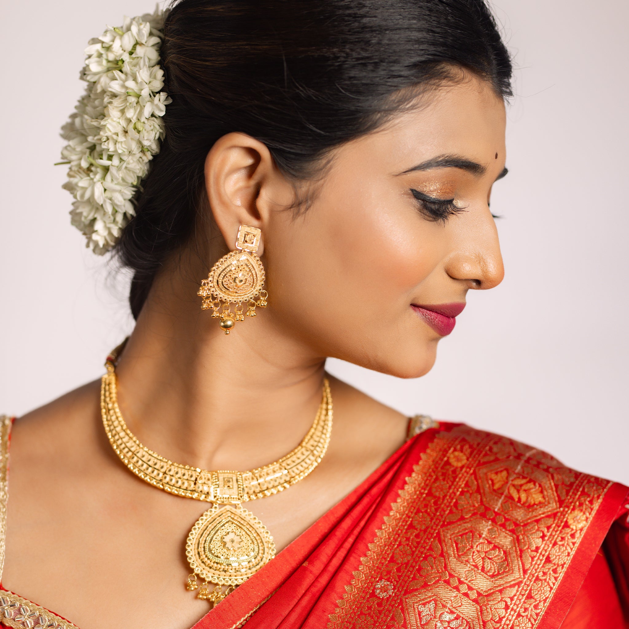 Woman wearing gold jewelry and a red saree , Gold Forming jewellery, short necklace gold, Samika by Tilloma , bridal set