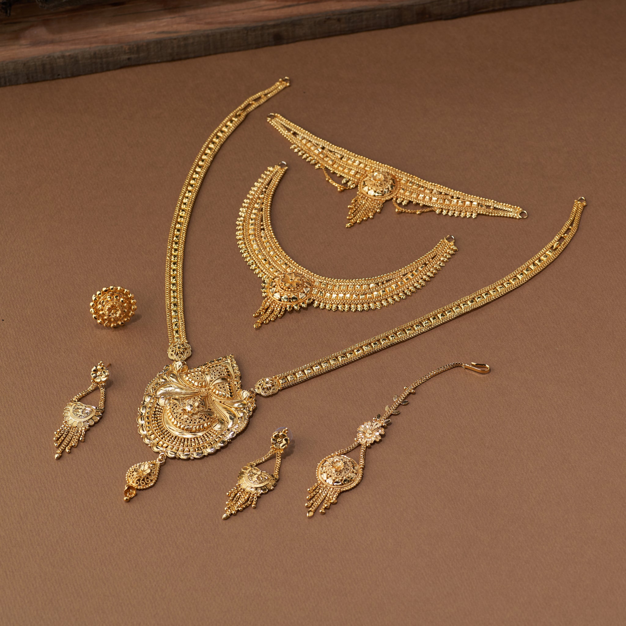 Traditional gold forming bridal jewellery set with short necklace, choker, long haaram, earrings, maang tikka and ring – perfect Indian bridal wedding jewellery with intricate temple-inspired design.
