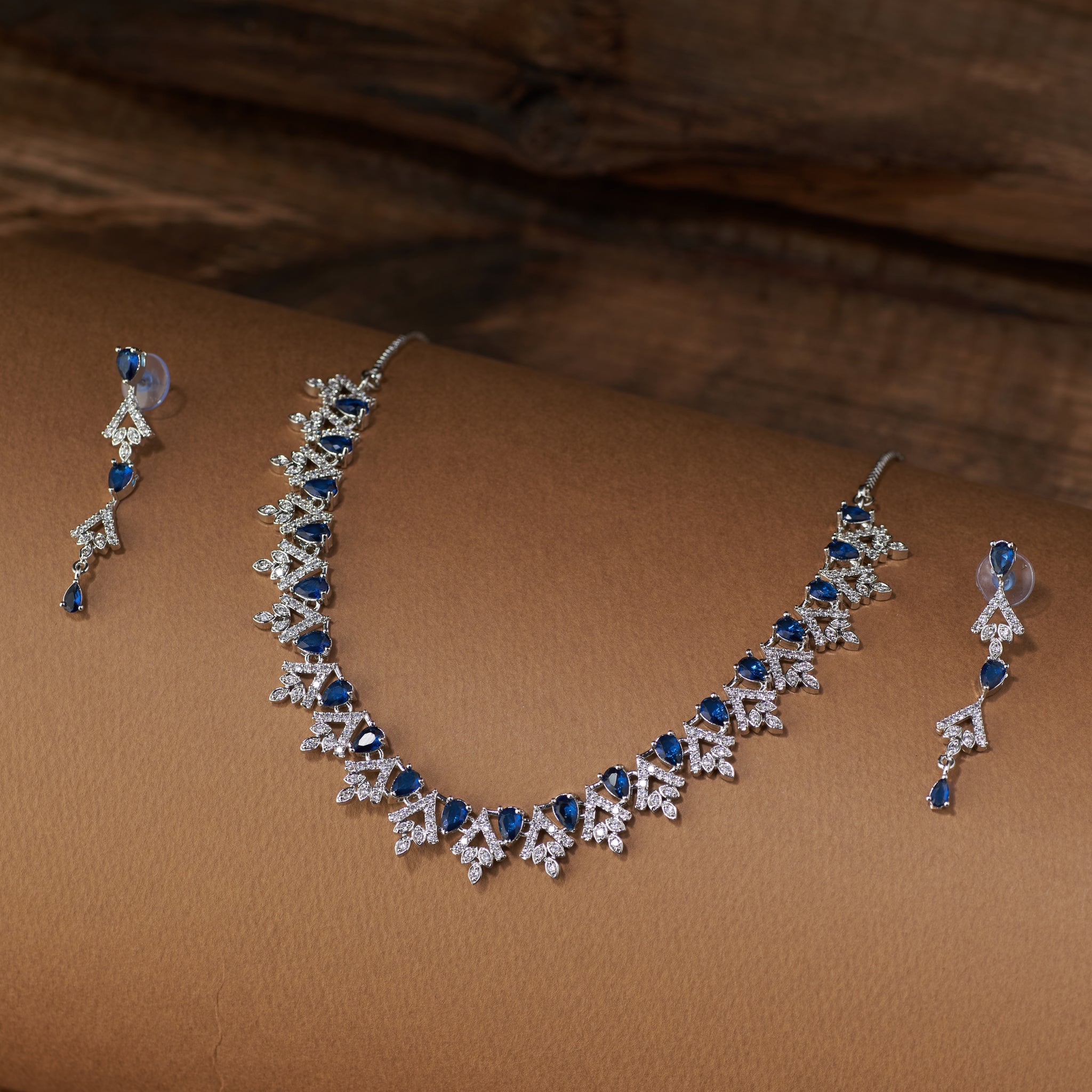Teardrop Necklace and earrings with blue cubic zircon stones on a brown surface