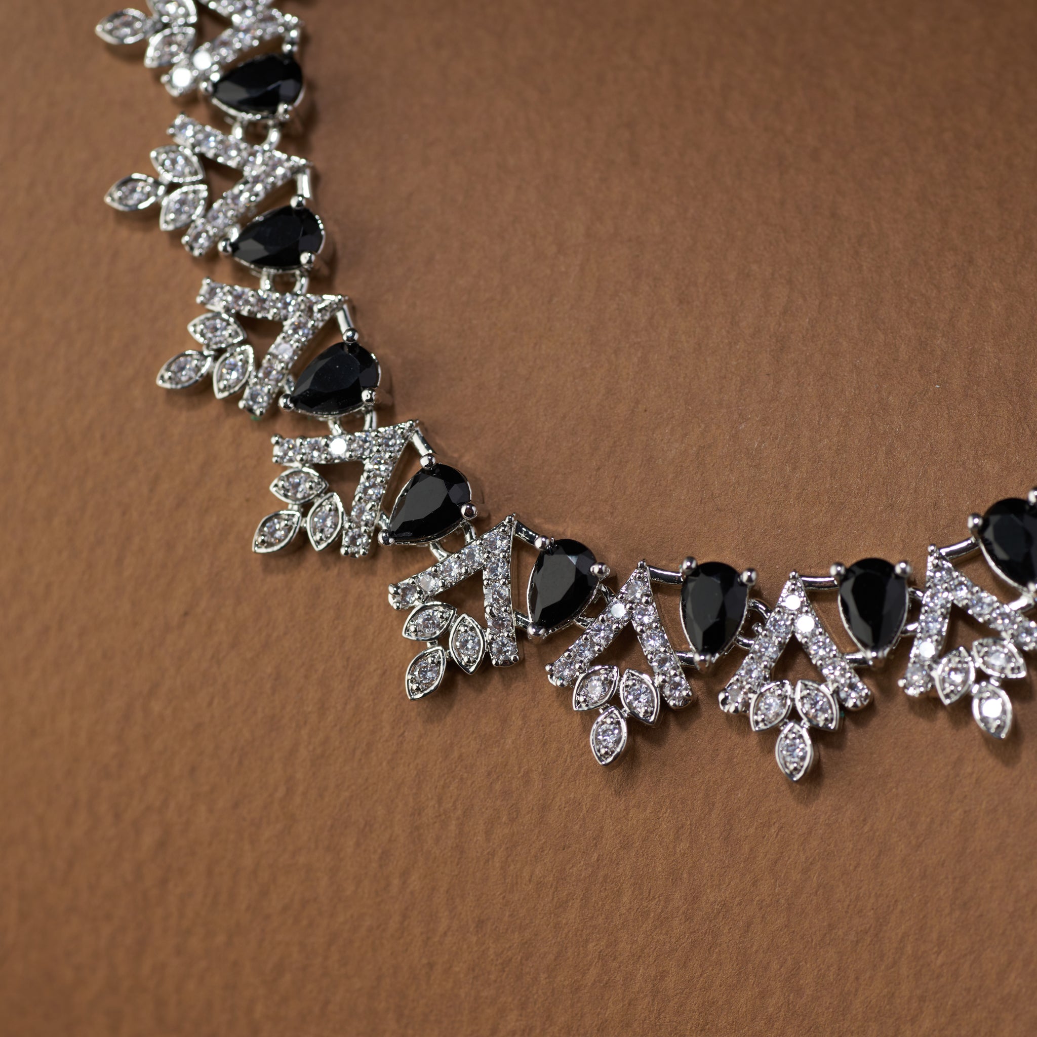 Teardrop Necklace and earrings with black cubic zircon stones  and silver accents on a brown background