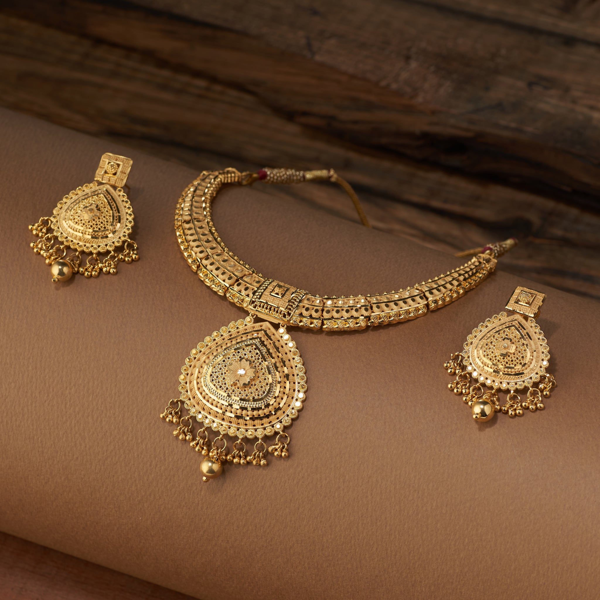 Gold necklace and earrings set on a brown fabric background. Gold Forming jewellery, short necklace gold, Samika by Tilloma , bridal set