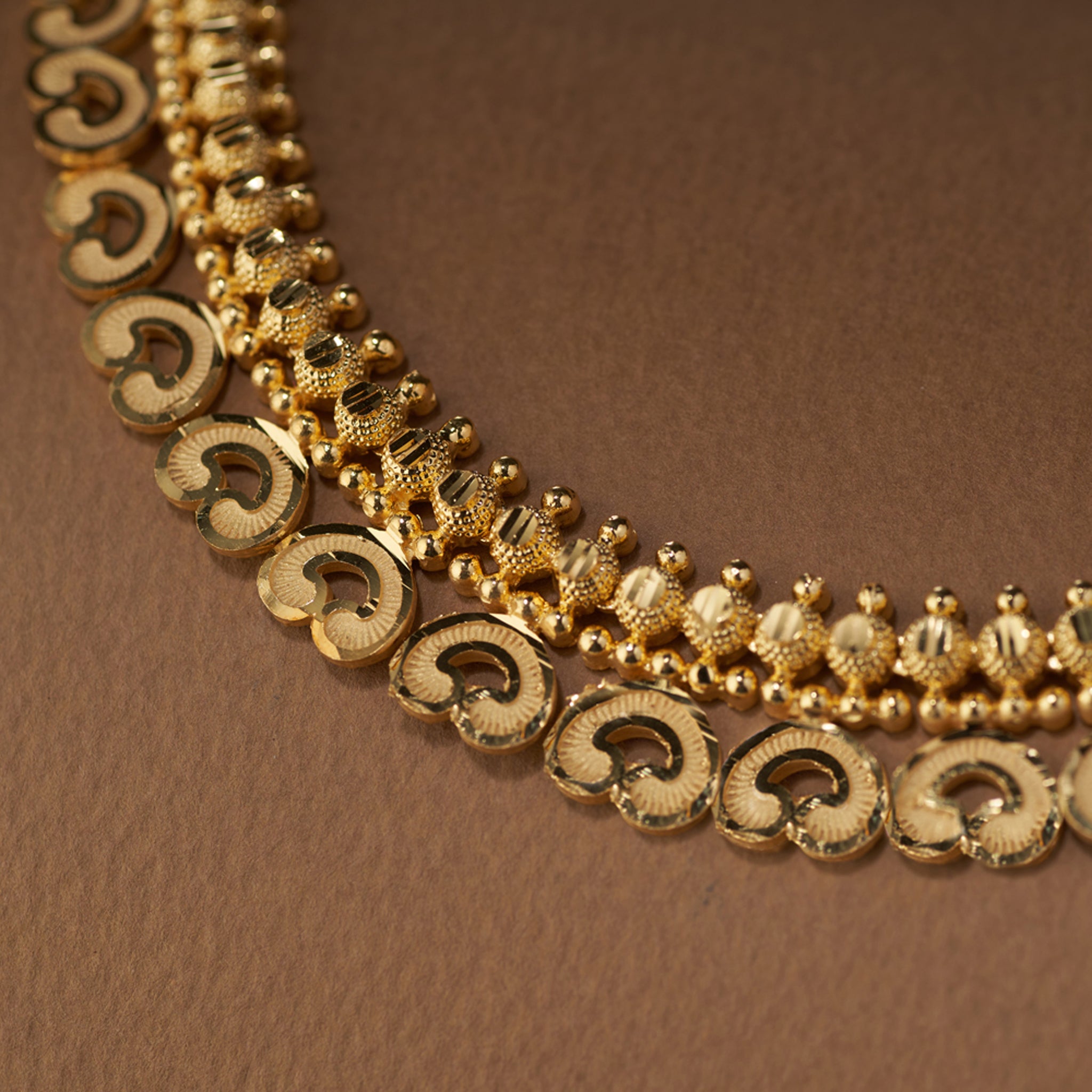 High gold-forming necklace set with intricate carved motifs, paired with matching designer earrings, close up