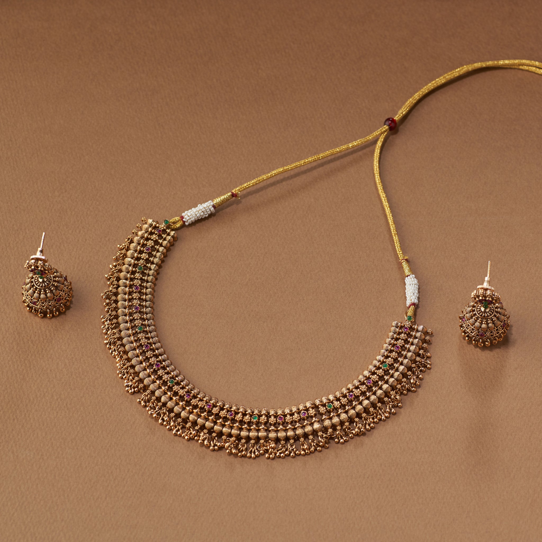 "South Indian antique gold temple choker necklace set with traditional earrings displayed on brown background"
